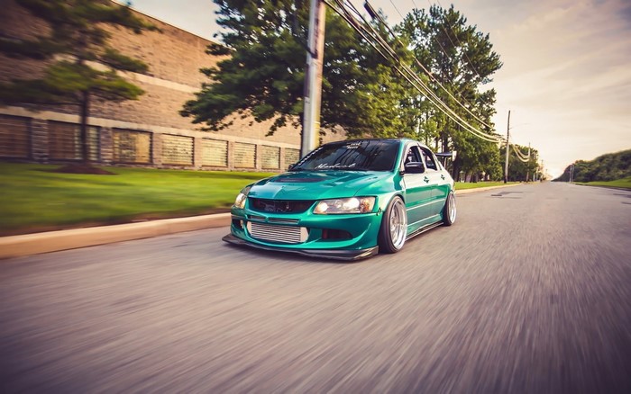 Green Mitsubishi Lancer Evolution VIII driving on road