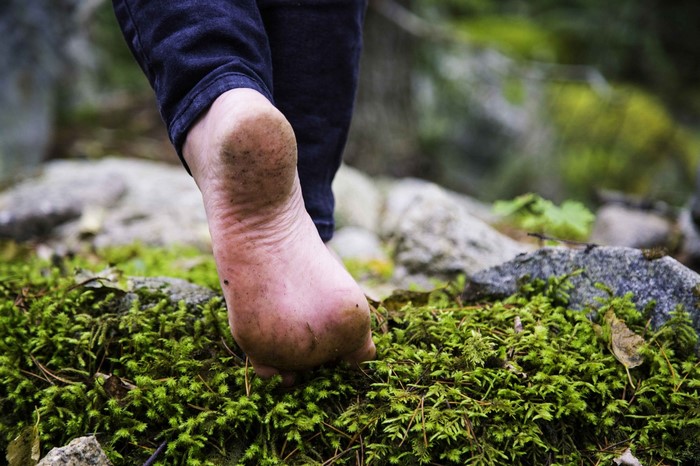 Barefoot person walking on mossy ground