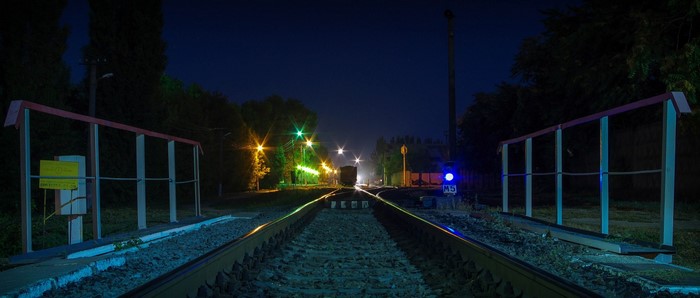 Night railway crossing with train lights
