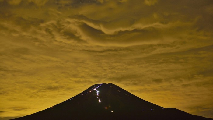 Mount Fuji at night with climbers and clouds