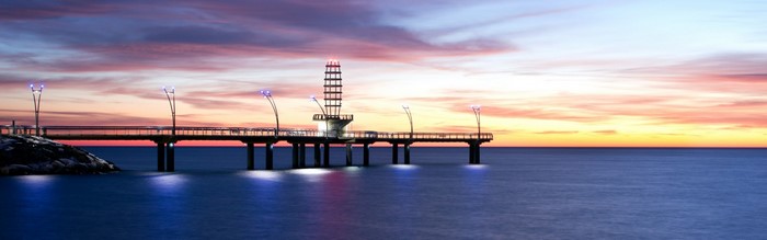 Pier with lights at sunset over the sea