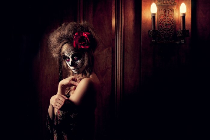 Woman with sugar skull makeup and red rose