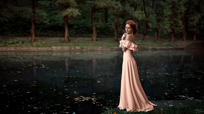 Woman in a peach dress by a lake