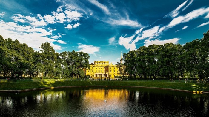 Palace reflected in a lake with trees and clouds