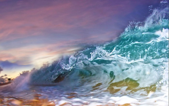 Ocean wave crashing at sunset with colorful sky