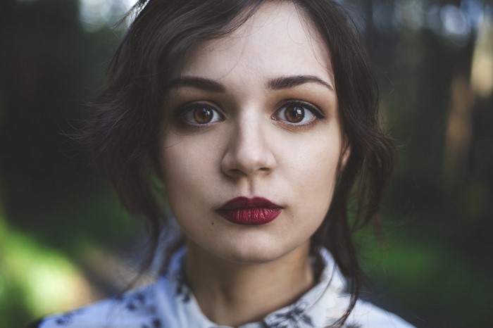 Close-up portrait of a young woman with dark hair and dark red lipstick