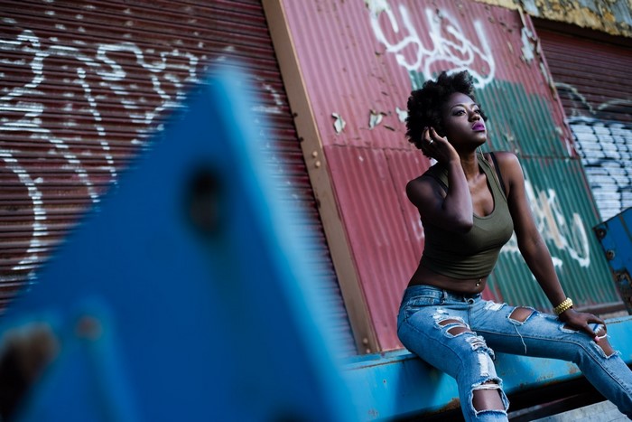 Woman in torn jeans sitting by graffiti wall