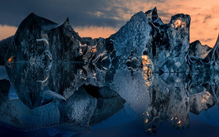 Icebergs reflecting in water at sunset