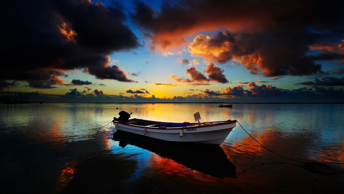 Boat on the water at sunset with colorful clouds