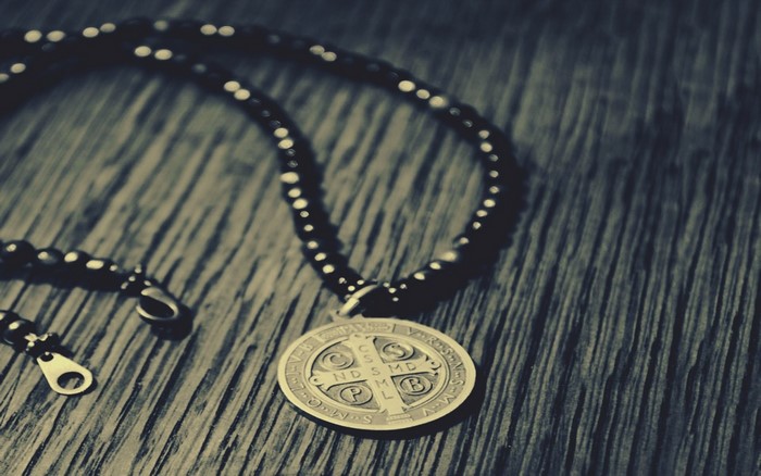Saint Benedict of Nursia medal necklace on wooden surface