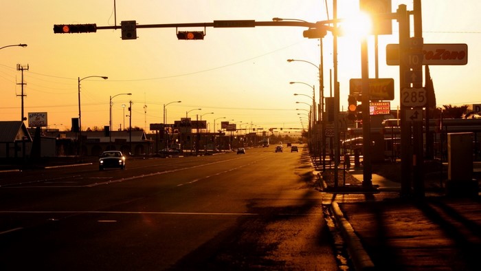 Sunset over a highway with traffic lights and signs