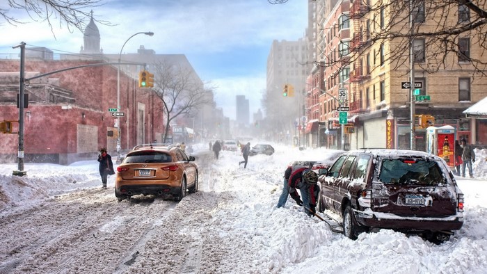 Street scene during a blizzard with cars stuck in snow