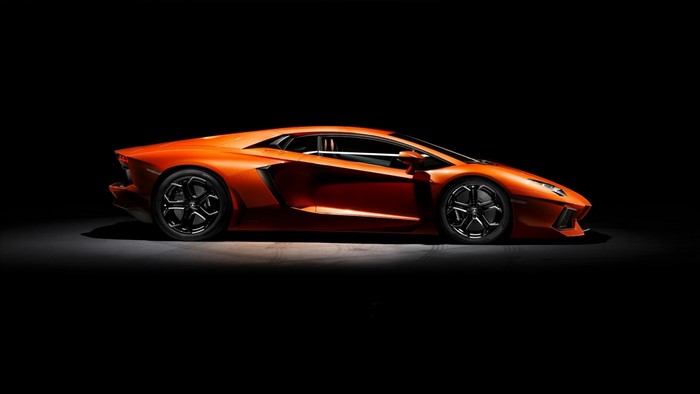 Orange Lamborghini Aventador parked on a dark surface