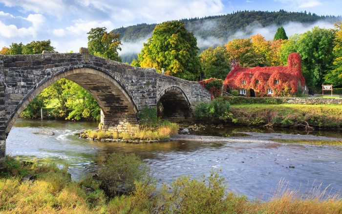 Stone arch bridge over a river in Wales during autumn