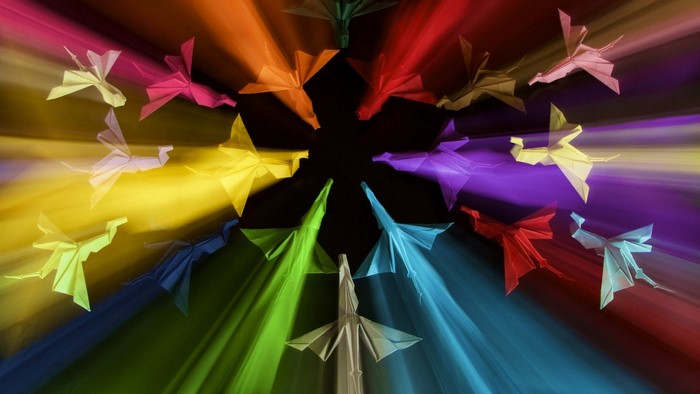 Origami birds in a rainbow of light trails