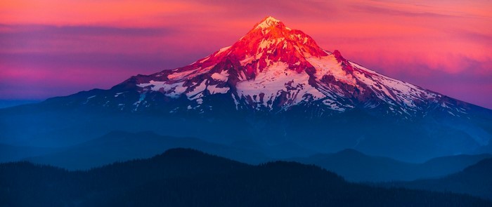 Snow-capped mountain peak illuminated by sunrise