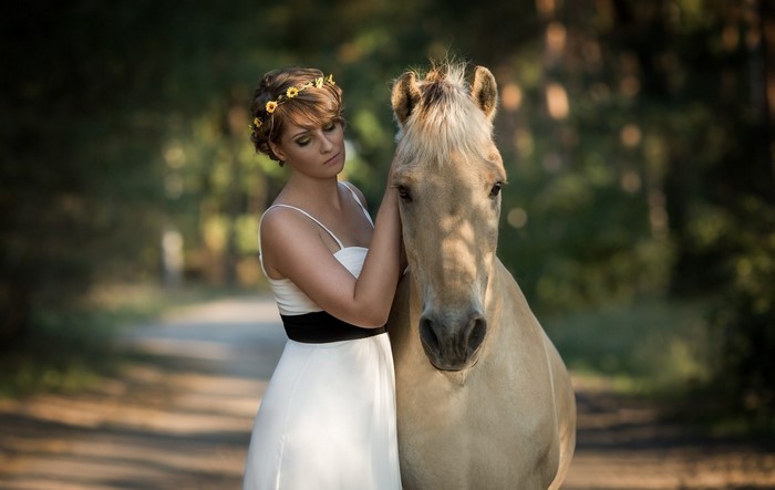 Woman in white dress with flower crown and horse
