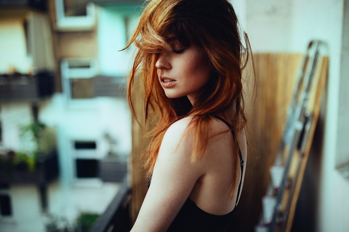 Redhead woman with eyes closed on a balcony