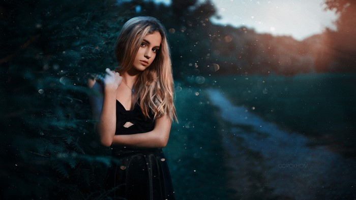 Woman in black dress in a forest at dusk