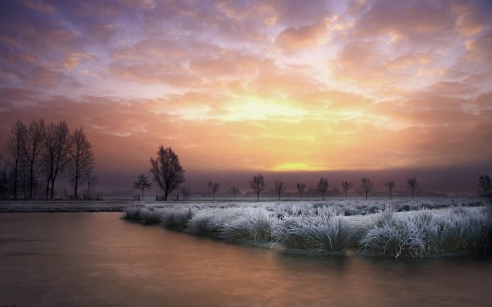 Winter sunrise over frosted landscape with river