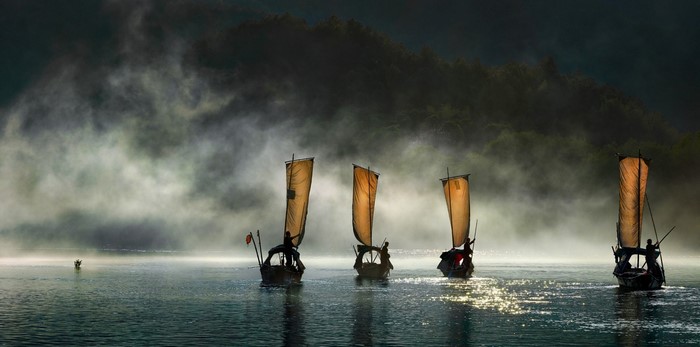 Boats sailing on a misty river at dawn