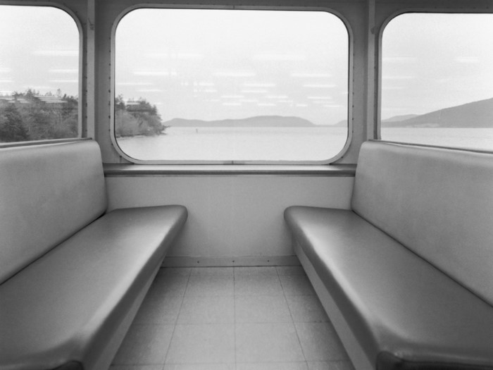 Interior of a ferry with seats and windows overlooking water