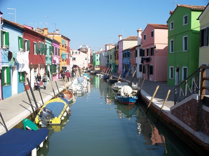 Colorful houses along a canal with boats in Burano, Italy