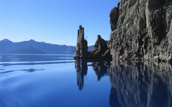 Rock formations in a blue lake with mountains