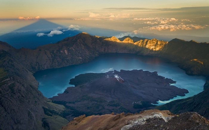 Volcanic crater lake with shadow of mountain at sunrise