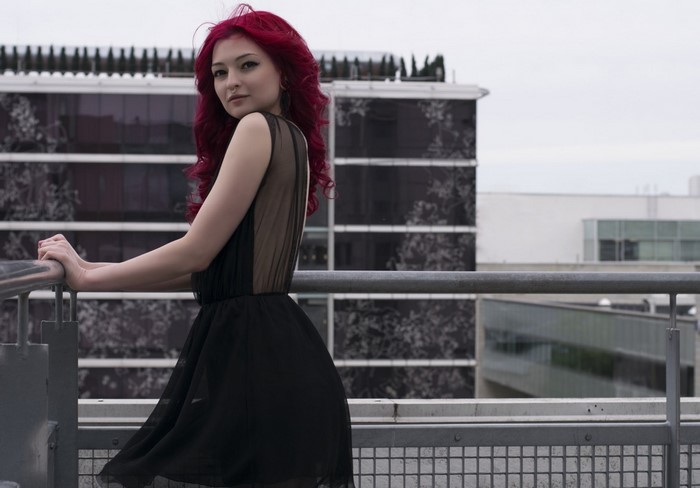 Woman with red hair in a black dress on a balcony