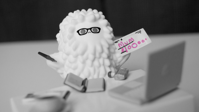 Fluffy toy character with glasses holding a note