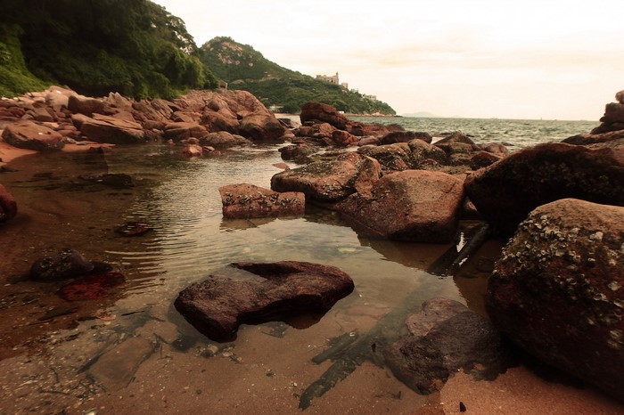 Rocky coastline with calm water and green hills
