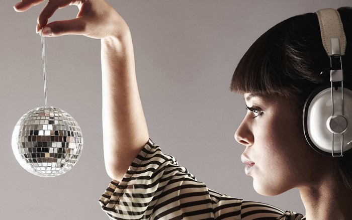Woman with headphones holding a disco ball