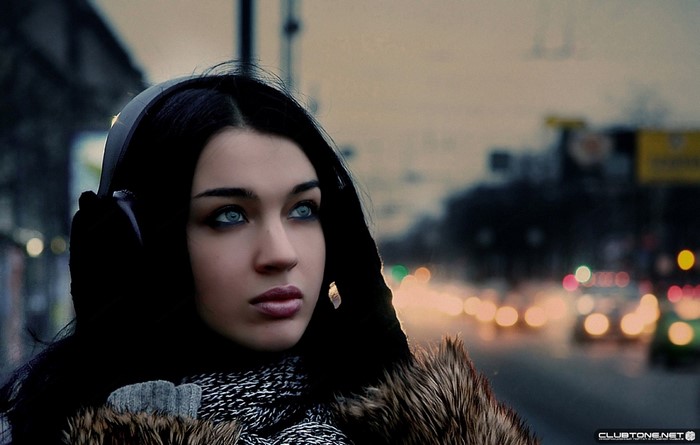 Woman with headphones and fur coat in urban setting