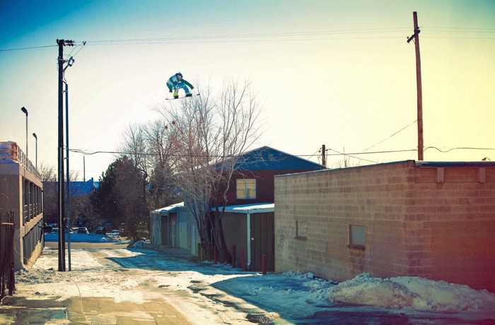 Snowboarder jumping in a snowy alley