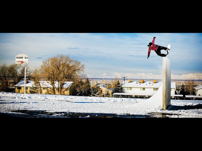Snowboarder performing a trick on a jump with mountains in the background