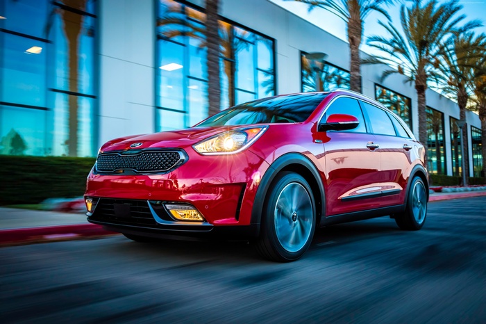 Red Kia Niro crossover driving on a street