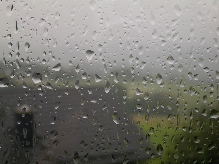Raindrops on a window pane with blurred background