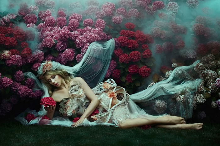 Woman in flower dress lying in hydrangeas