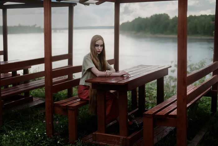 Woman sitting at a wooden table by a lake