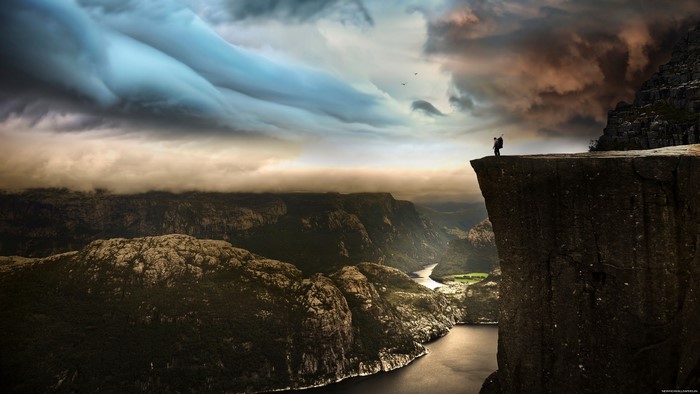 Man on cliff overlooking valley and river in Norway
