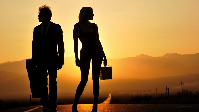 Couple silhouetted on a road at sunset