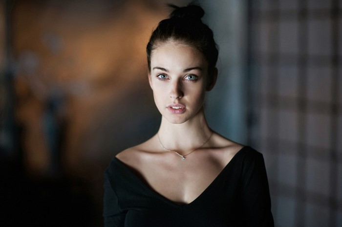 Woman with blue eyes and hair bun wearing black dress