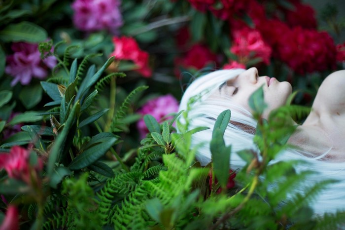 Woman with white hair lying in flowers