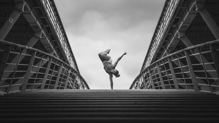 Woman performing a handstand on a bridge