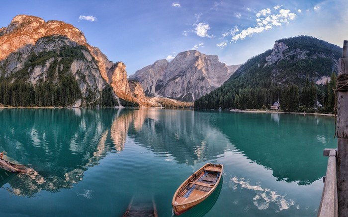 Wooden boat on a turquoise lake with mountains and forest