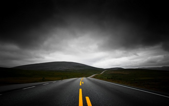 Road through a dark, cloudy landscape