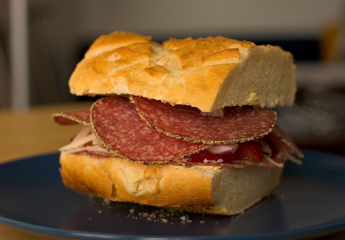 Sandwich with salami and vegetables on a blue plate