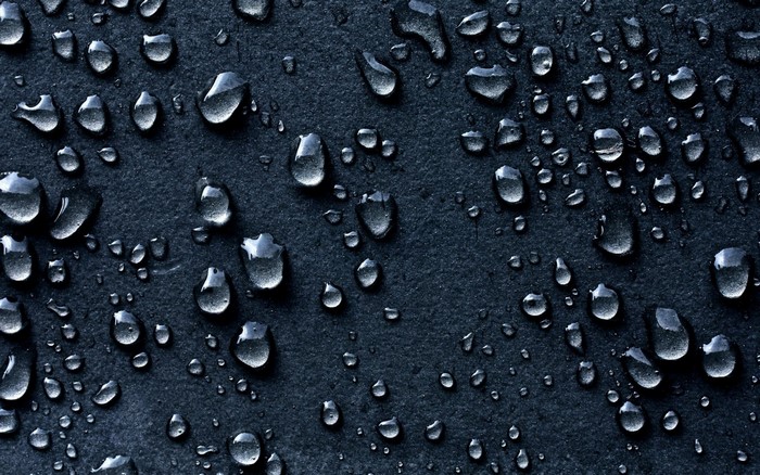 Water drops on a dark textured surface