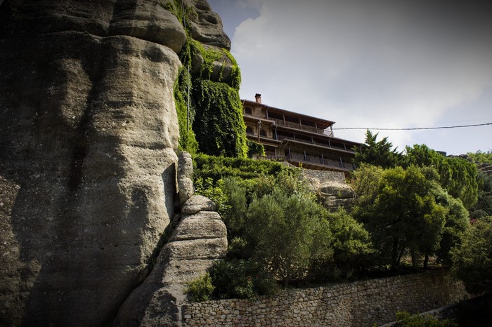 Monastery built on a rock cliff with trees and sky